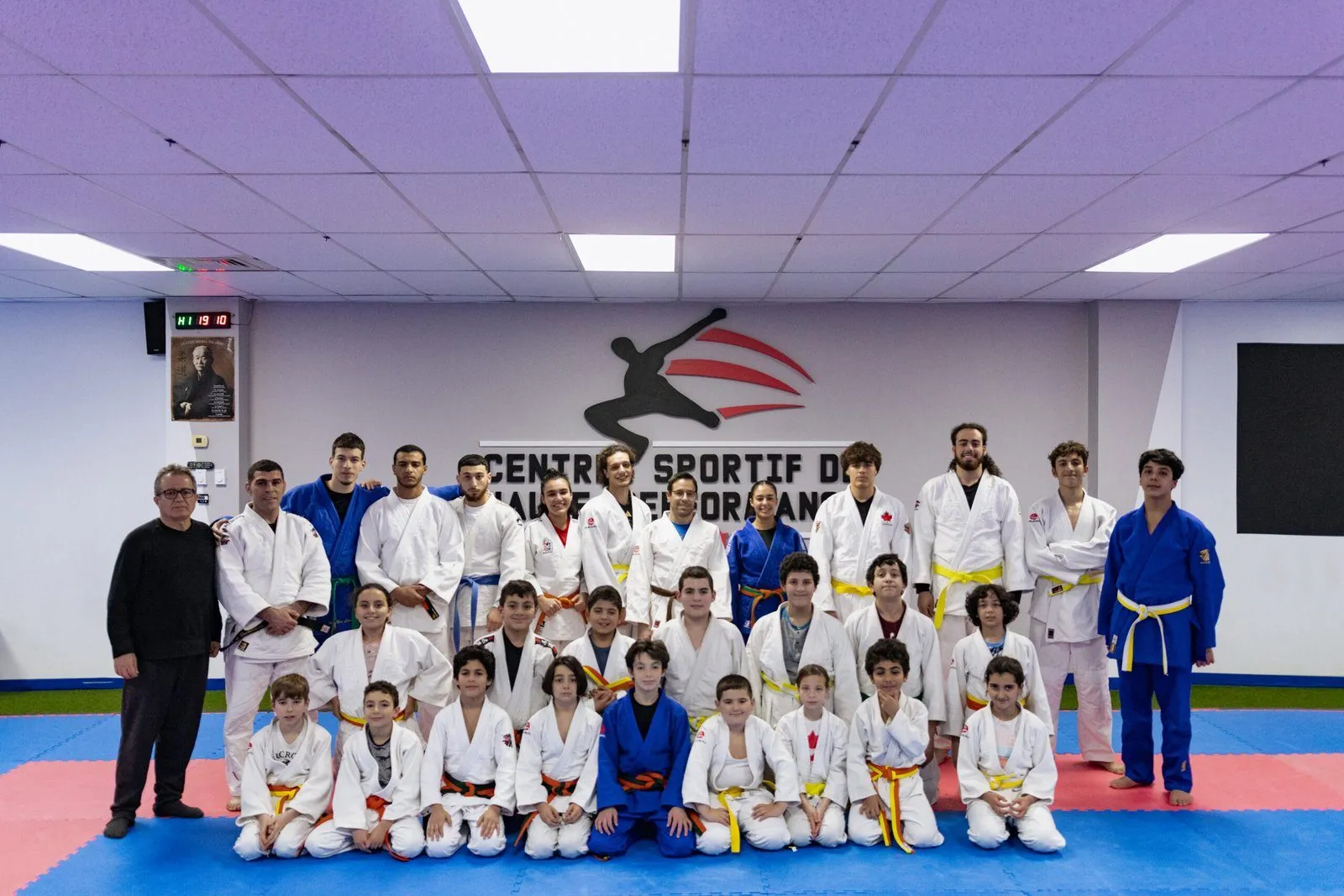 Photo de groupe des athlètes et coachs du CSHP devant le mur du dojo