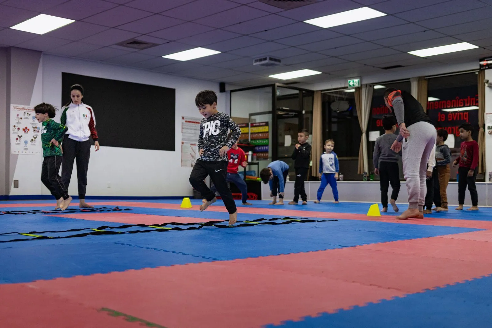 Enfants du programme parascolaire franchissant une échelle d'agilité au dojo
